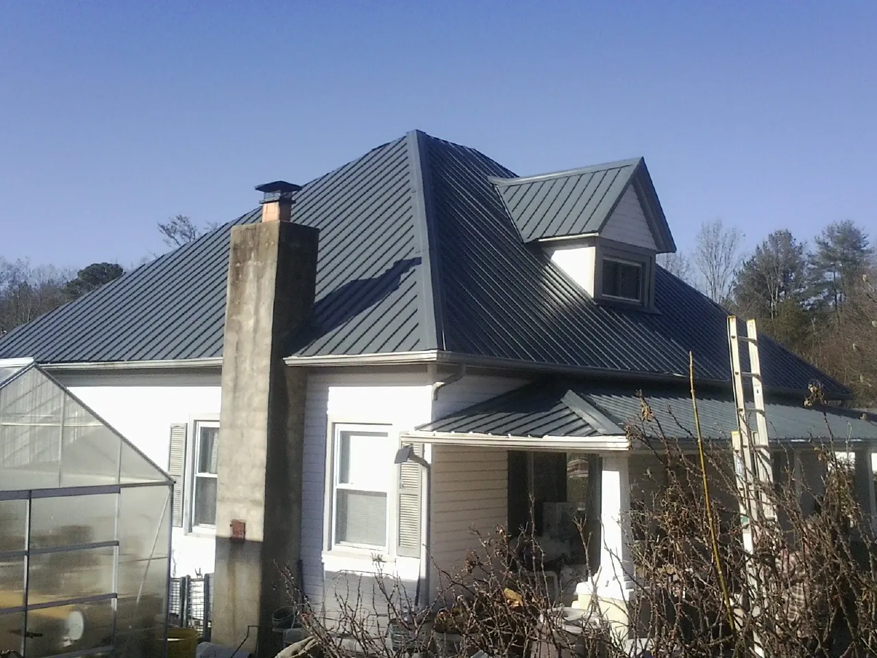 Dark blue standing seam metal roof on a white farmhouse with dormer — Slate & Tile Roof Repair by Roofing Brothers in Centralia